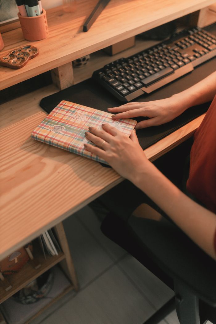 Warm-toned home office desk with keyboard and notebook, highlighting a cozy workspace ambiance.