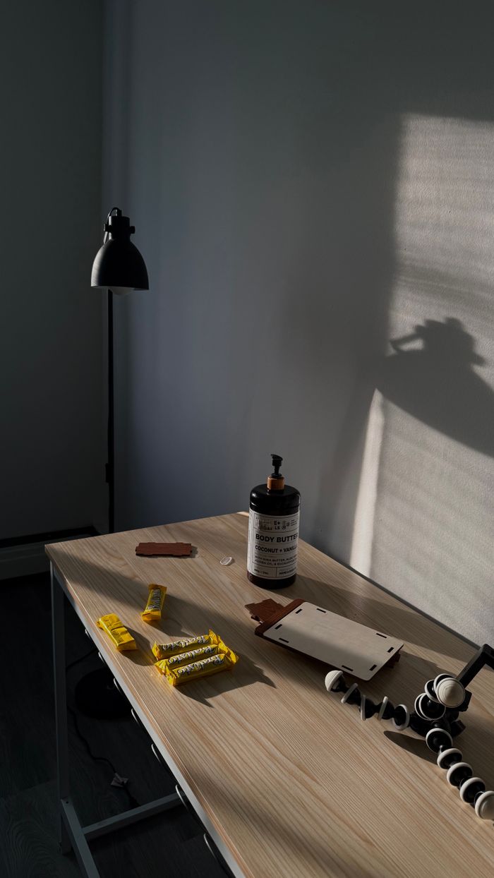 A minimalist office desk with a lamp, shadows, and assorted stationery in natural light.